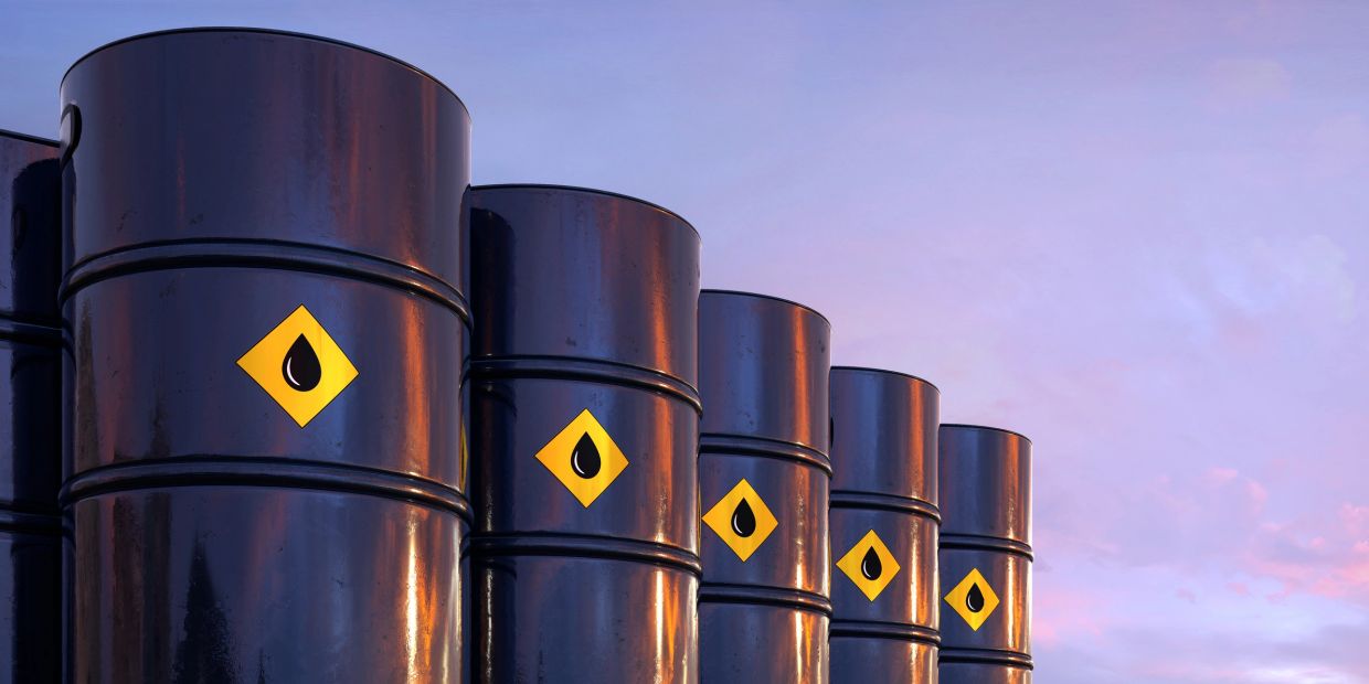 Row of black oil barrels with droplet warning symbols.