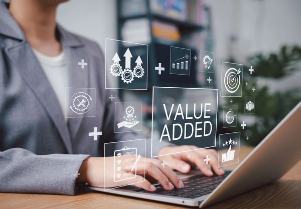 Businesswoman typing on laptop with value added concept icons floating.