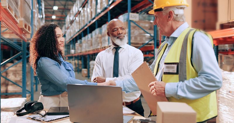 Business people, document and shaking hands in warehouse for logistics, meeting for supply chain collaboration. Import team, tech or handshake in storage for export deal, service agreement or welcome