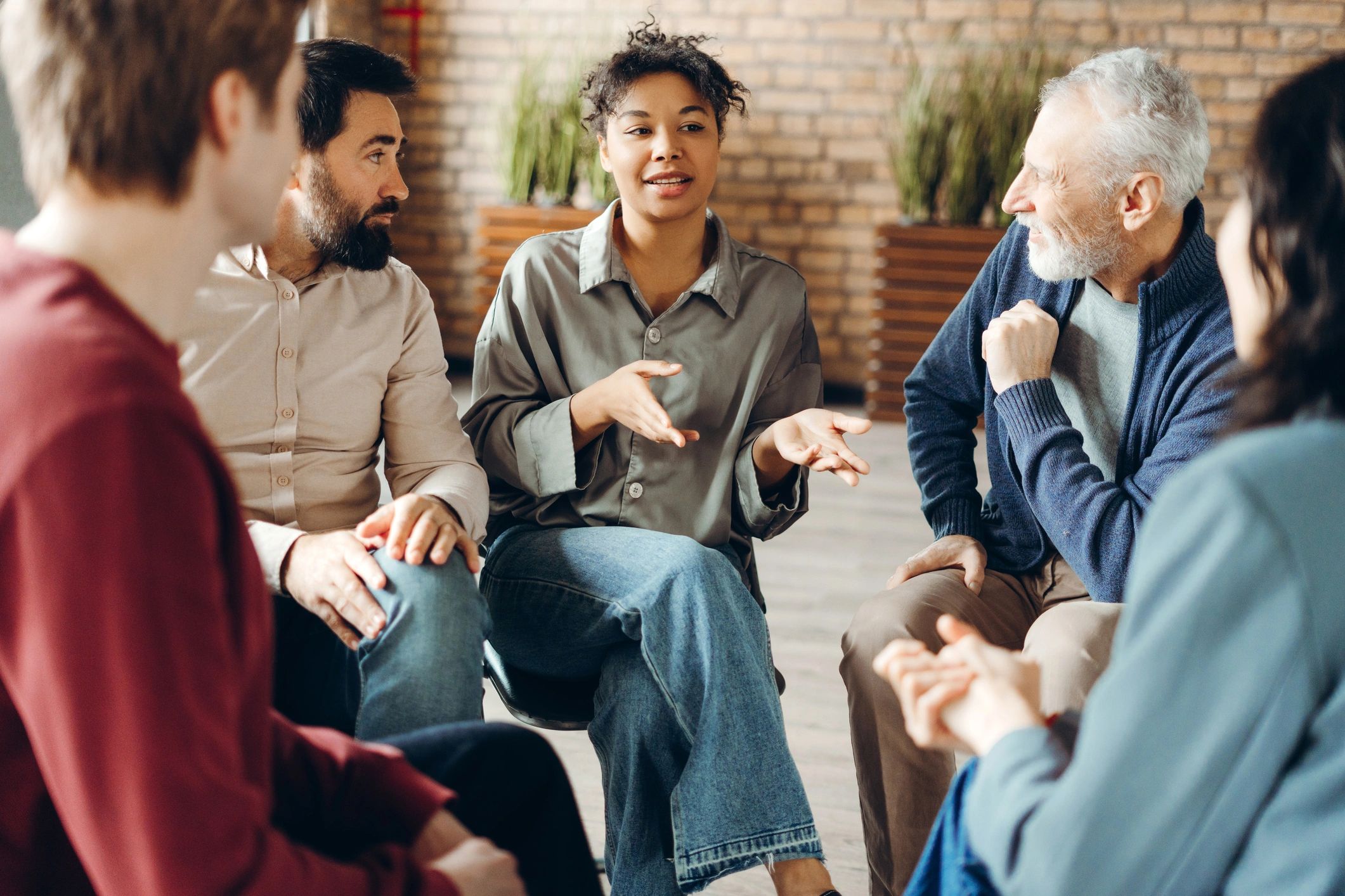 Diverse group engaged in a lively discussion, seated in a circle indoors.