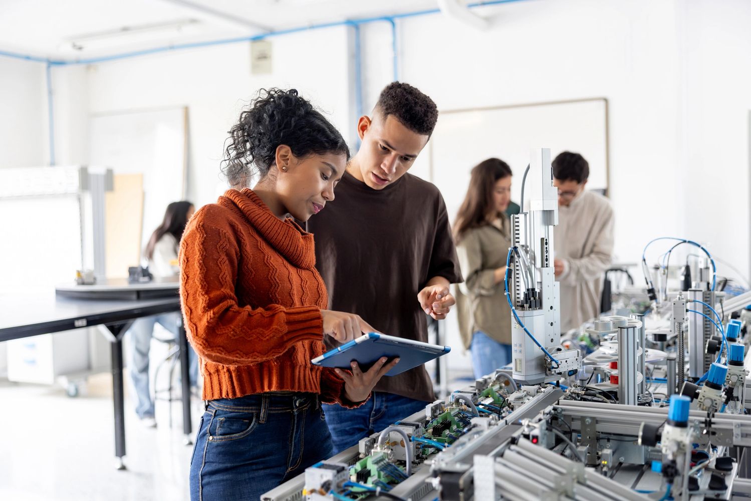 Two students working on a robotics project with a tablet in a lab.