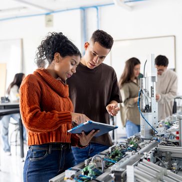 Two students working on a robotics project with a tablet in a lab.