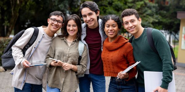 Group of five smiling students outdoors.