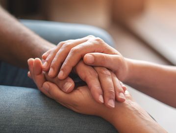 Two people holding hands in a comforting gesture.