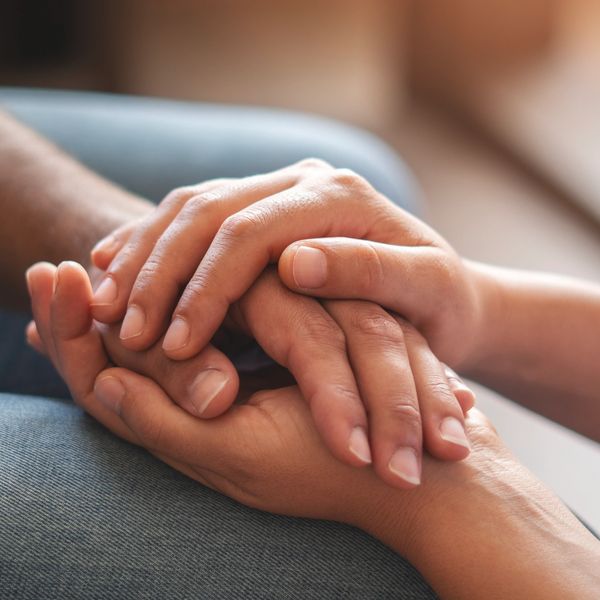 Two people holding hands gently.