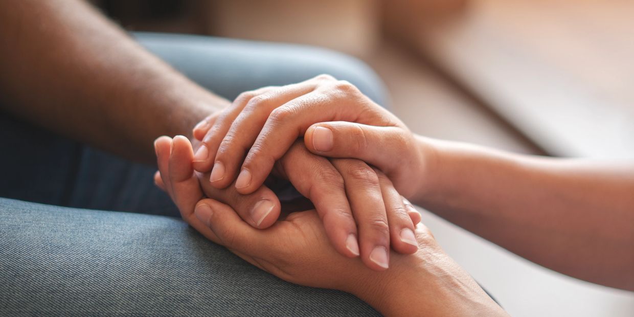Two people holding hands supportively.