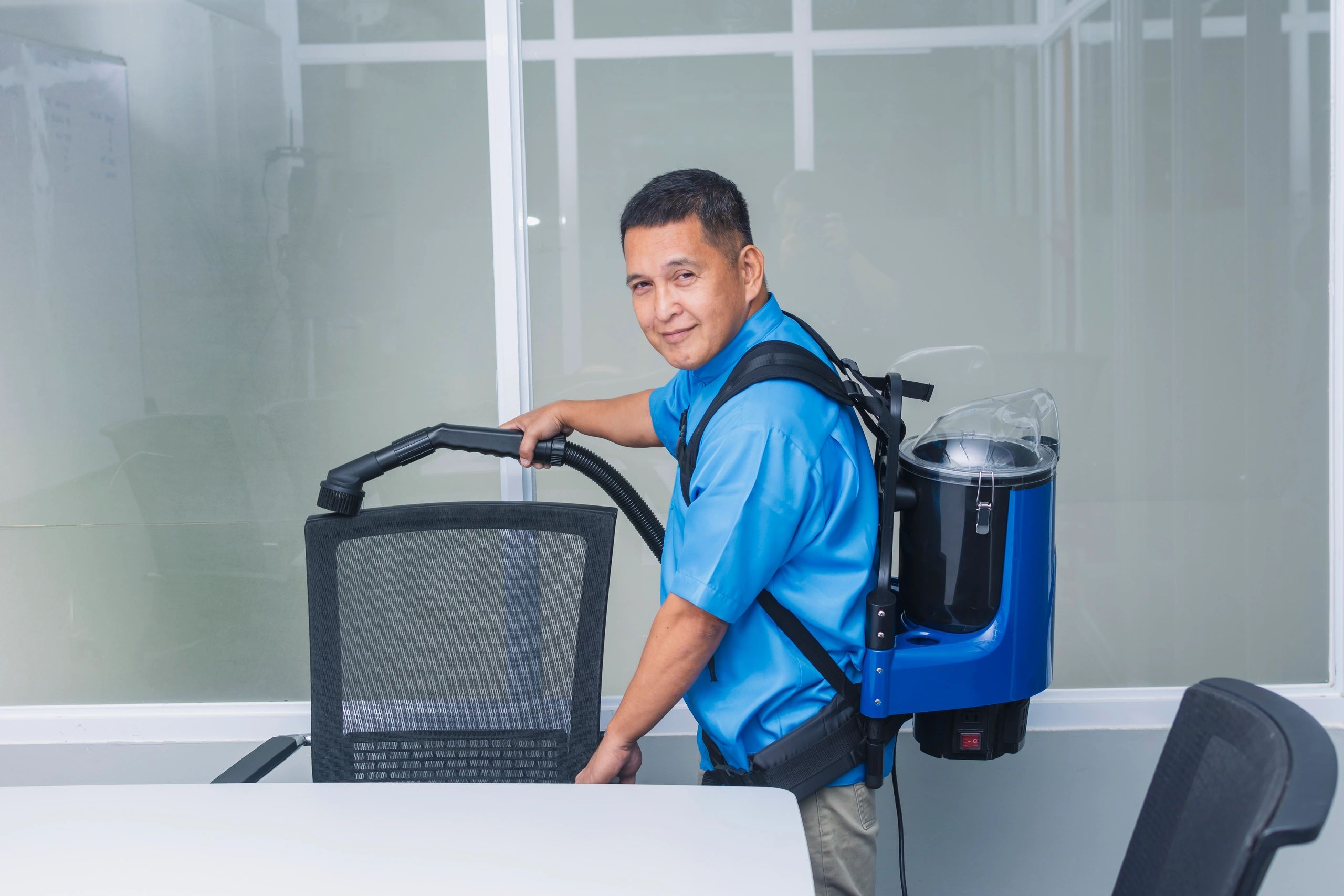 A man cleaning an office with a commercial backpack vacuum cleaner