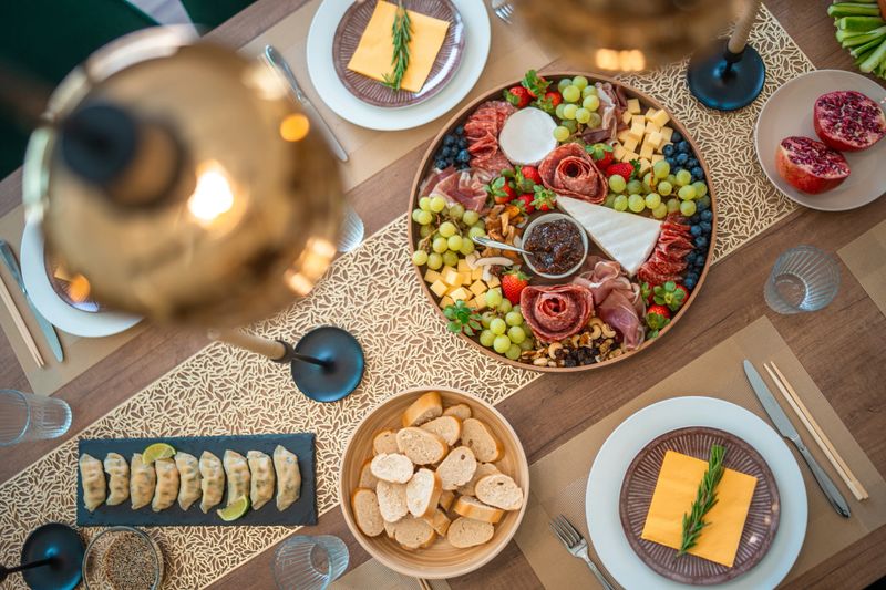An elegantly arranged dinner table featuring a charcuterie board with meats, cheeses, fruits, bread, and dim decorative lighting for a cozy ambiance.