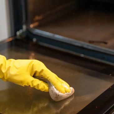 A gloved hand wiping an oven door