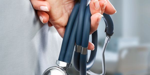 Close-up of a hand holding a stethoscope in a medical setting.