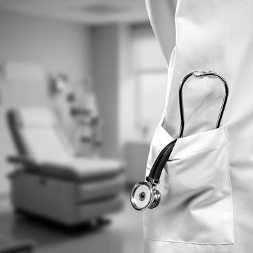 Stethoscope tucked into a doctor's white coat pocket in a medical exam room.