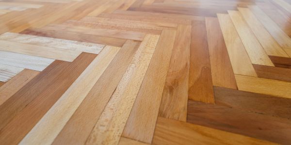 Close-up of a wooden parquet floor with a herringbone pattern.
