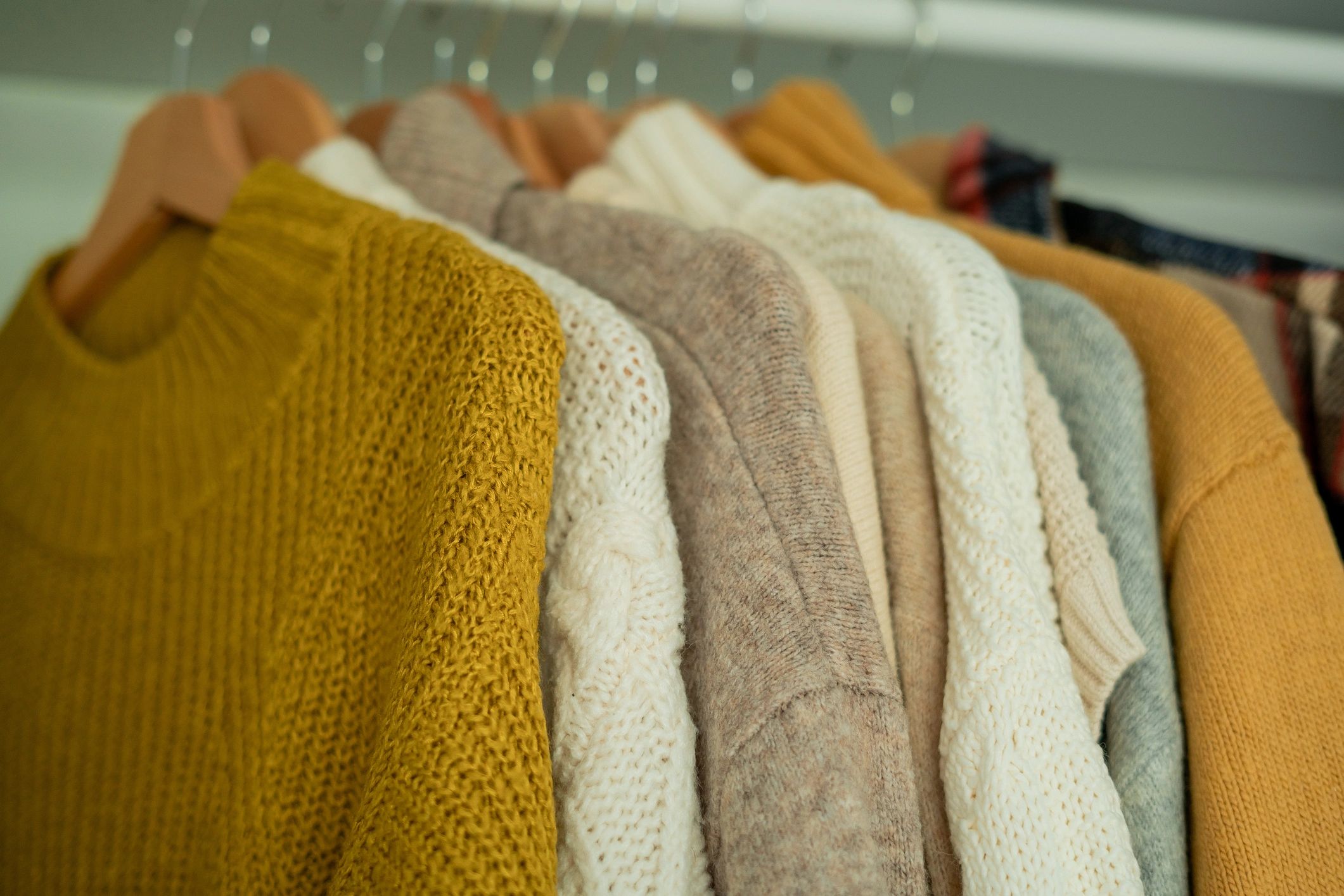 Close-up of colorful knitted sweaters on hangers.