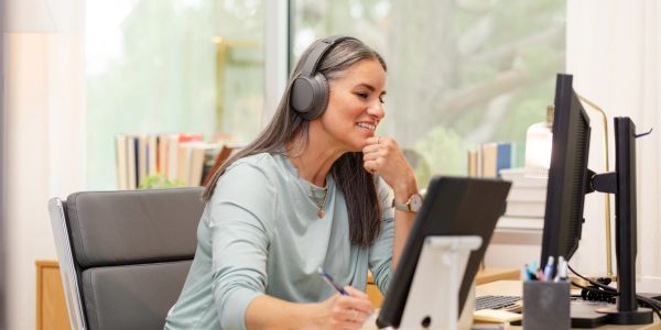 Femme souriante avec casque travaillant à l'ordinateur.