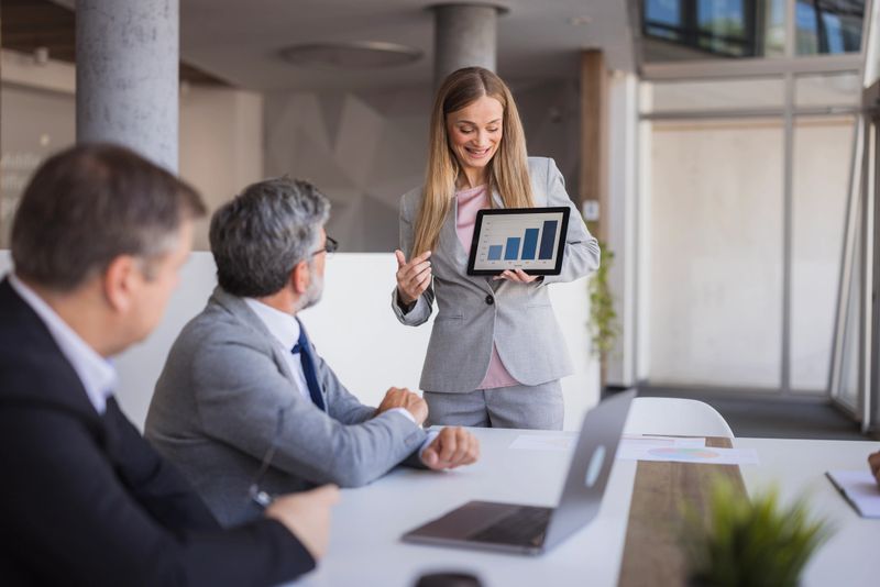 Businesswoman showing positive growth data on tablet to colleagues during a meeting in the office