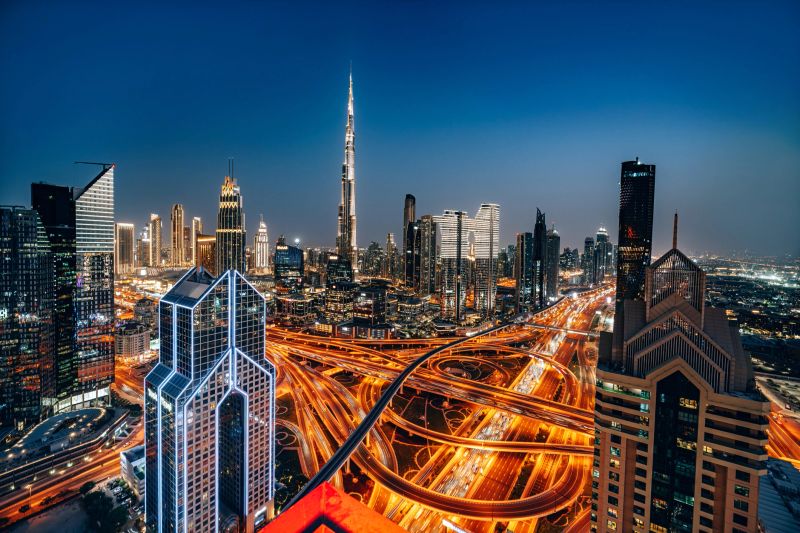Stunning twilight view displaying the intricate network of Sheikh Zayed Road and the iconic Dubai skyline illuminated against the evening sky. Tall skyscrapers and city lights create a vibrant, modern scene.