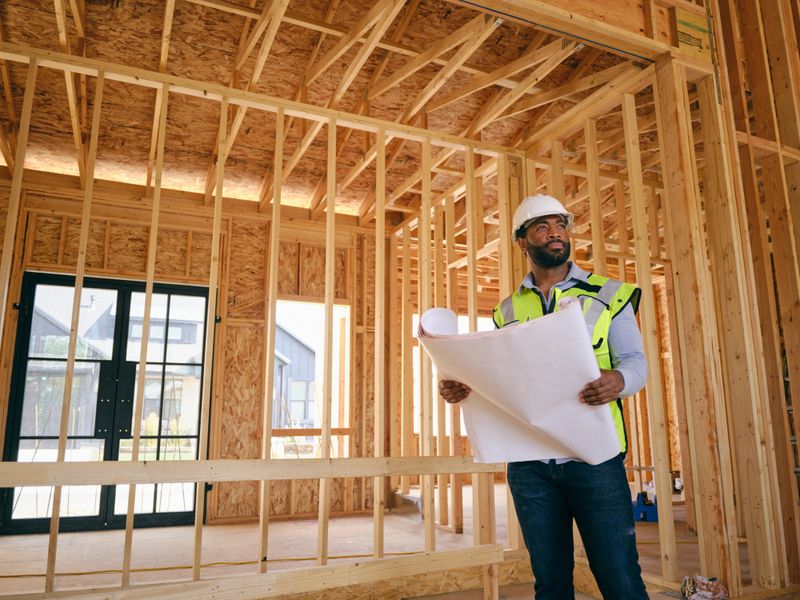 A construction worker inspecting a home under construction.