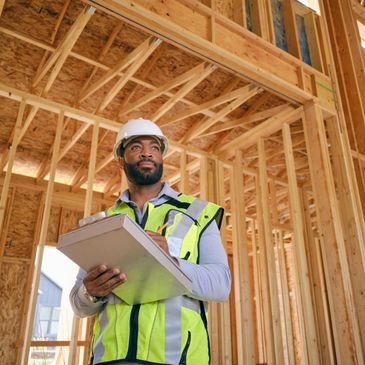 Construction worker inspecting a wooden frame structure with a clipboard.