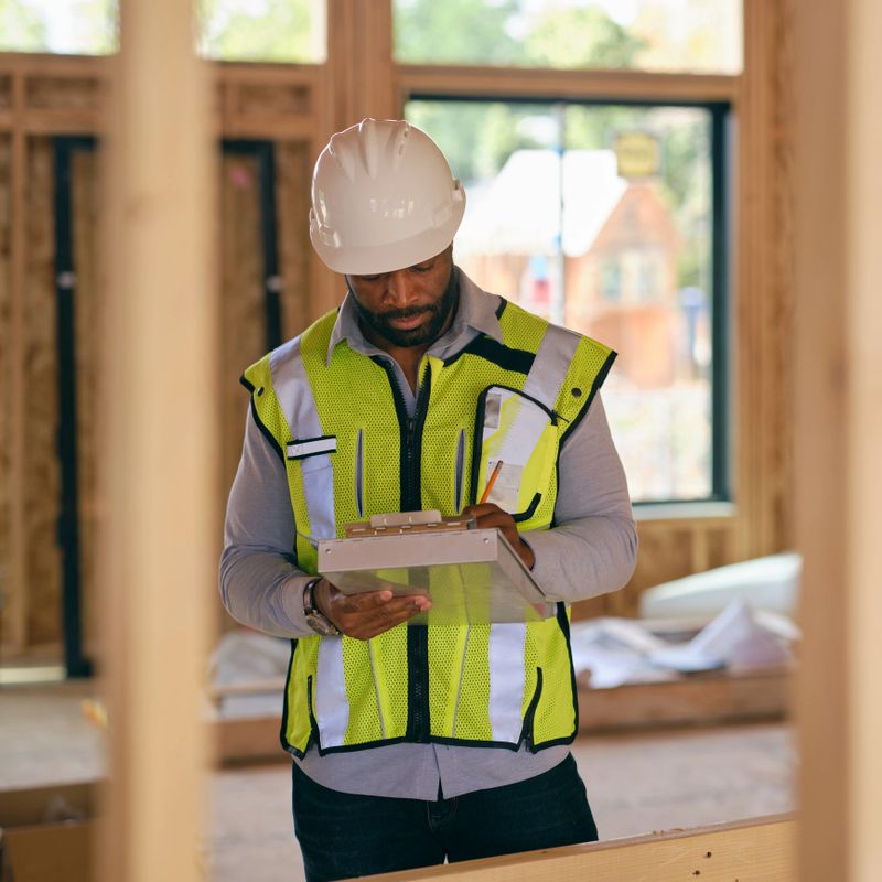 A construction worker inspecting a home under construction.