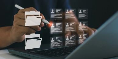 Person interacting with digital folders and profiles on a laptop screen.