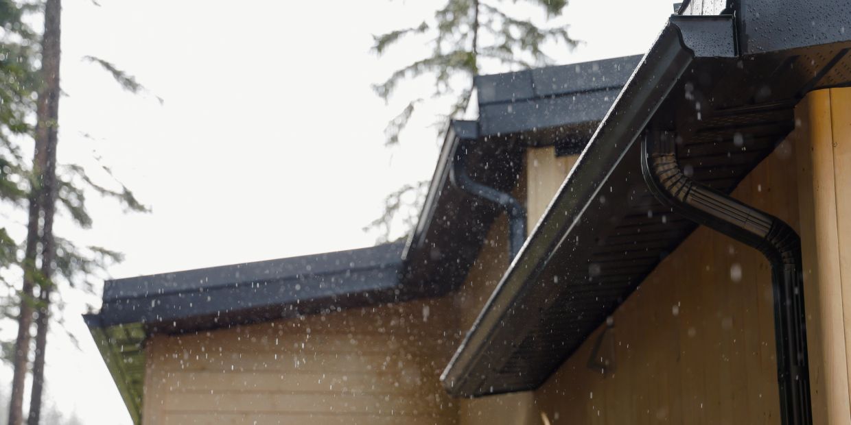 Rain falling near a house roof and gutter.