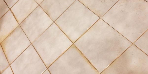 Close-up of dirty white tiles with grime in grout lines.