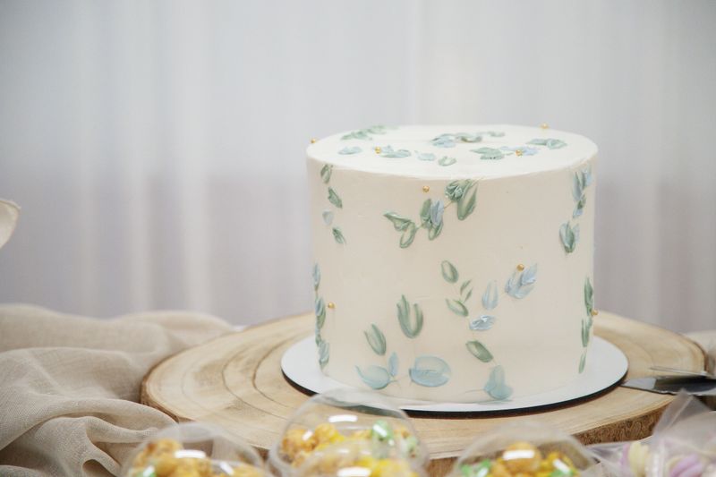 Elegant pastel buttercream cake displayed as a centerpiece on a table, decorated for a festive summer event perfect for intimate celebrations.