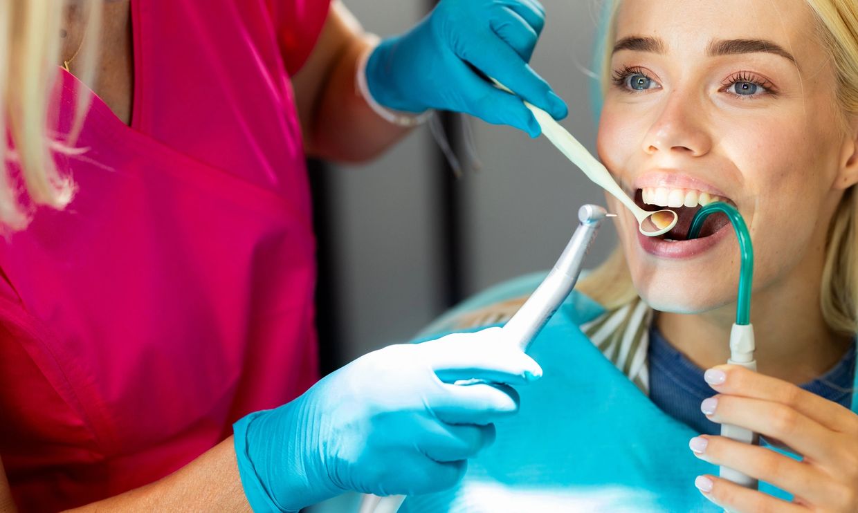 Dentist treating a female patient with dental tools.