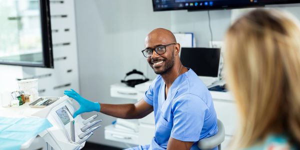 Smiling healthcare professional in blue scrubs using medical equipment.