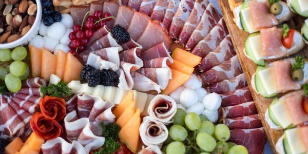 Assorted charcuterie board with meats, fruits, and cheese.