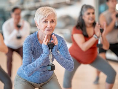 Senior woman exercising with a dumbbell in a group class.