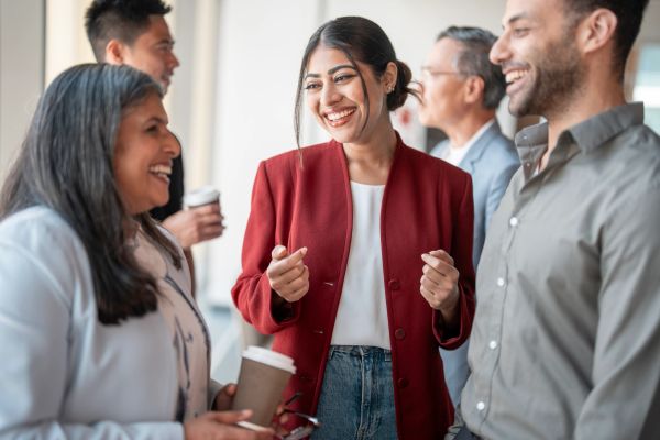 A group of people happily chatting holding coffee cups.