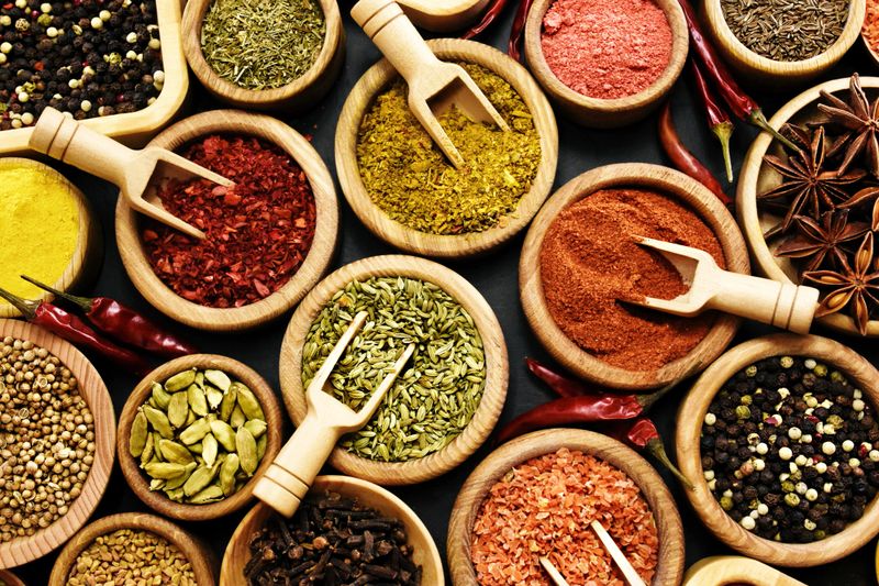 Colorful mix of herb and spice varieties: curry and coriander, turmeric and cumin, paprika and pepper, mustard and salt, cardamon and oregano and saffron. Selective focus, shallow DOF