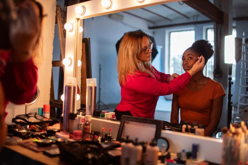 A diverse Gen Z girl receives professional makeup in a well-lit photography studio