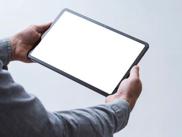 Person holding a tablet with a blank white screen.