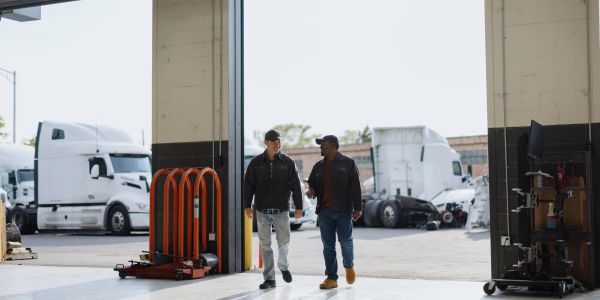 Two men walking inside a truck garage.