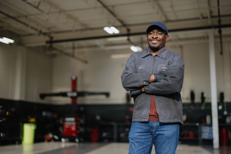 Portrait of a smiling african american mechanic standing with arms crossed in a car repair shop