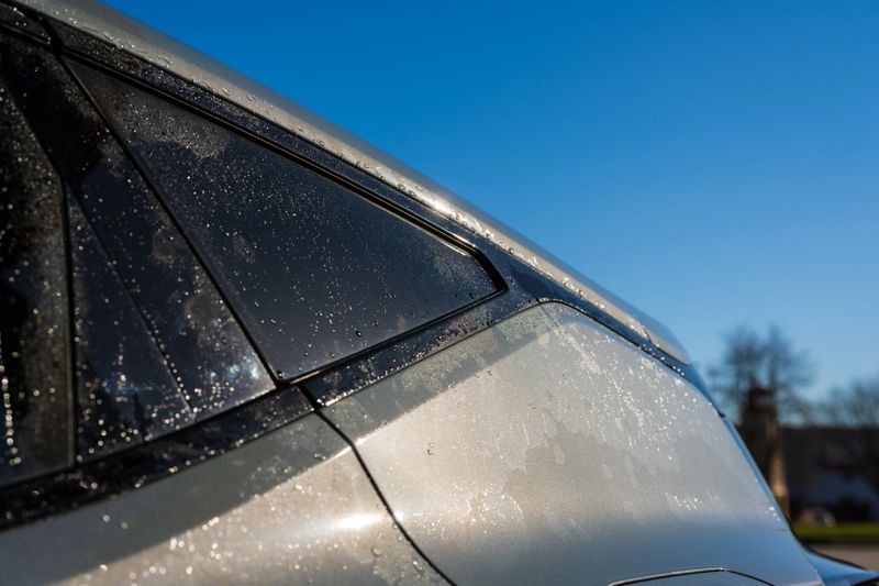 Modern silver car closeup with water drops.