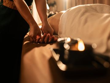 Person receiving a relaxing hand massage in a warm, candlelit room.