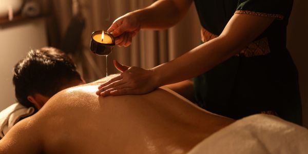 Person receiving an oil massage with a lit candle.