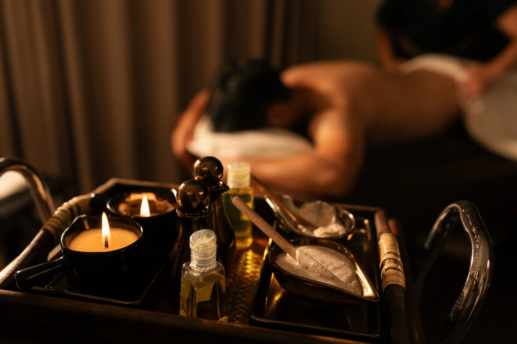 A person receiving a back massage with spa essentials in the foreground.