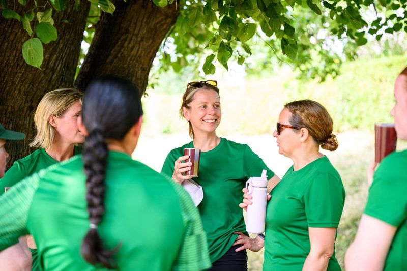 Mixed age range and ethnicity women and girls cricket teams playing match together outdoors in summer