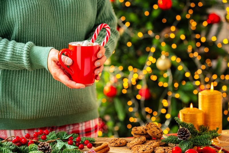 Sweet Christmas food: woman's hand holding hot chocolate marshmallow mug on cozy table with chocolate chips cookies. High resolution 42Mp studio digital capture taken with Sony A7rII and Canon EF 70-200mm f/2.8L IS II USM Telephoto Zoom Lens