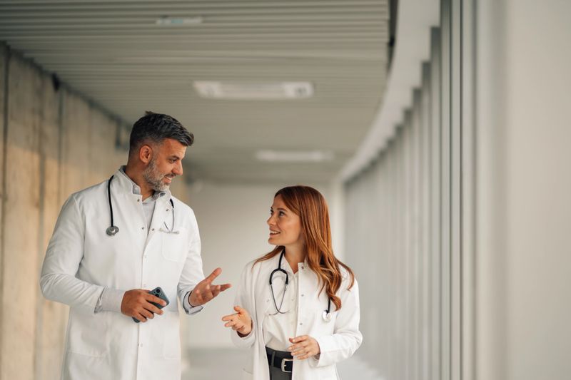Two doctors walking and talking in a modern hospital corridor, engaging in discussion and collaboration while sharing expertise and knowledge