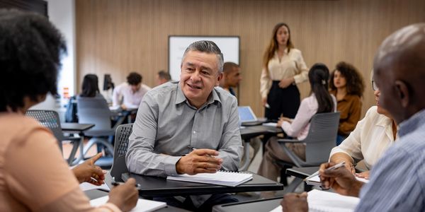 Adults engaged in a group discussion in a classroom setting.
