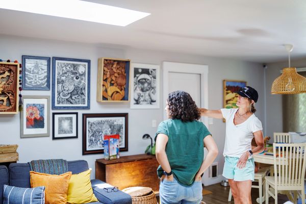 Two women discussing art on the wall in a cozy living room.