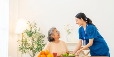 A nurse serving food to a senior woman.
