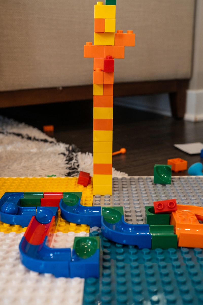 Child enjoys building a colorful track with plastic blocks on a play mat during the afternoon