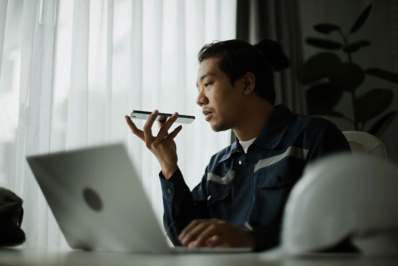 Asian man using AI voice assistant while working as a technician.