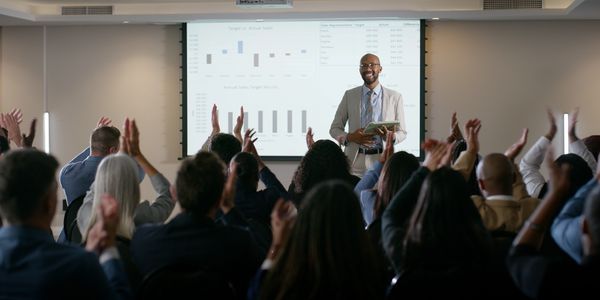 A confident businessman presenting sales data to an applauding audience.